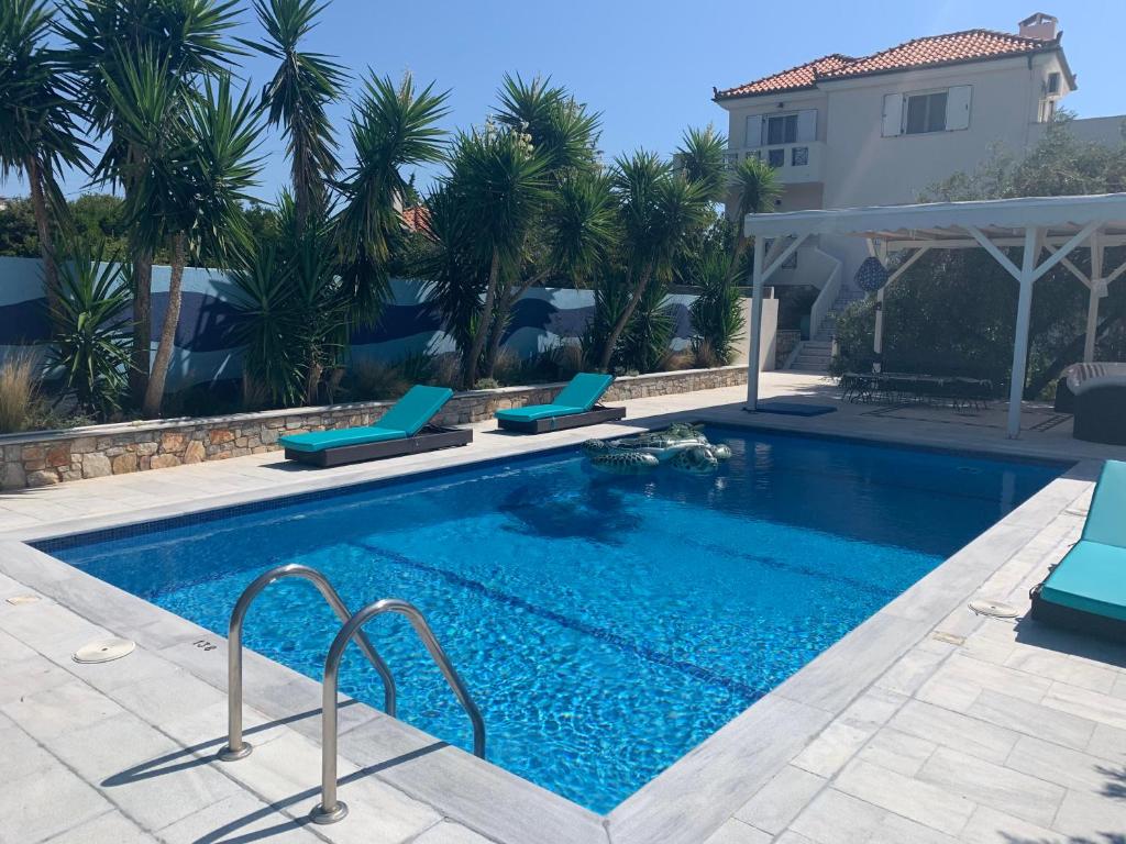 - une piscine avec 2 chaises et une maison dans l'établissement Chiqui luxury apartments, à vieille ville d'Alonissos