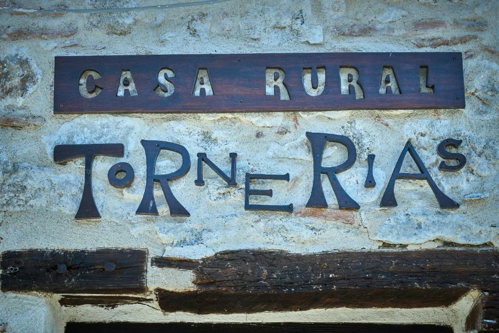 un cartello blu sulla strada sul lato di un muro di Casa Rural Tornerías a Cuerva