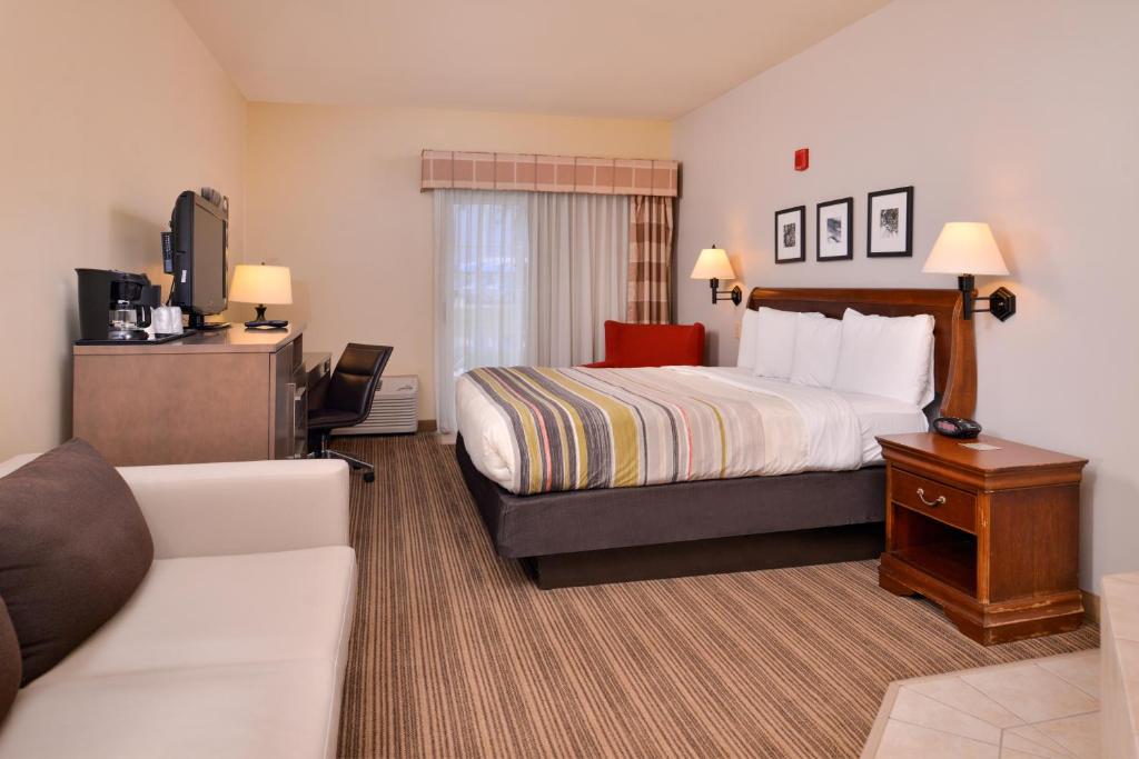 オマハにあるCountry Inn & Suites by Radisson, Omaha Airport, IAのベッドとソファのあるホテルの部屋