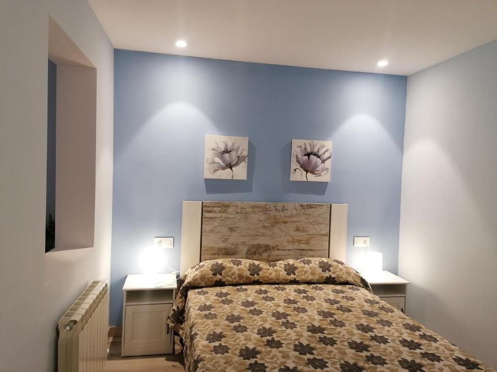 a bedroom with a bed with three paintings on the wall at Apartamentos El Cid in Molina de Aragón