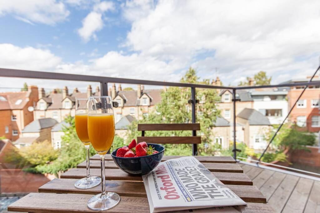 een tafel met een krant en een glas wijn en een fruitschaal bij Modern and chic city centre apartment with parking in Oxford