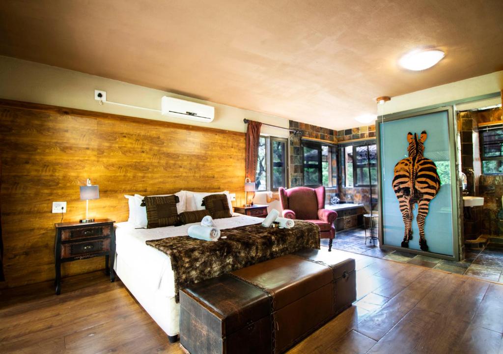 a bedroom with a bed and a zebra painting on the wall at Adventure Bush Villa in Marloth Park