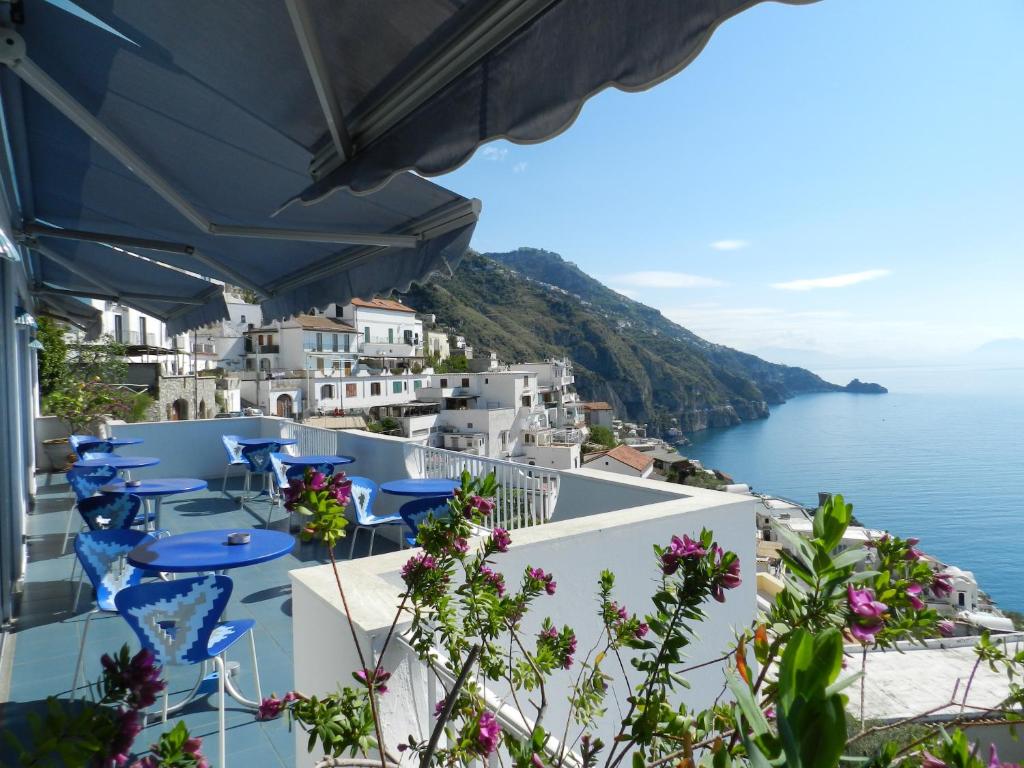 un balcón con sillas azules y vistas al océano. en Hotel Holiday, en Praiano