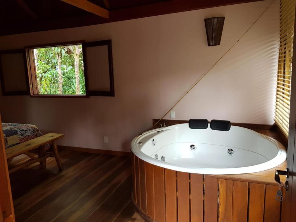 a large bath tub in a room with a window at Chalés Mathora in Visconde De Maua