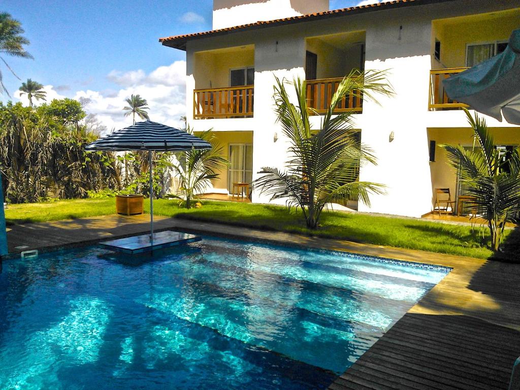 a swimming pool in front of a house with an umbrella at Pousada do Holandes Bahia in Barra Grande