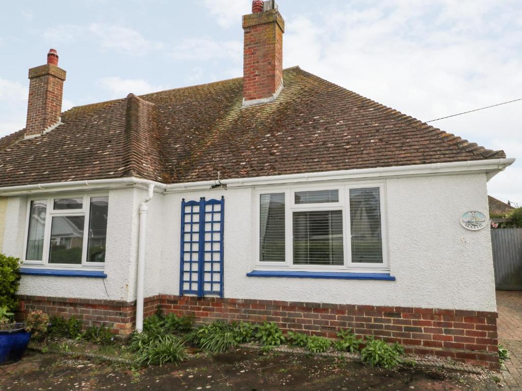 a white house with blue windows and a roof at Mouette in Peacehaven