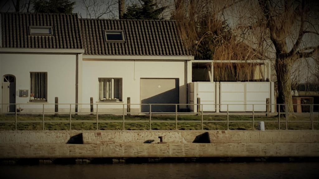 a white house with a fence in front of it at vakantiehuis Plassendale in Oudenburg