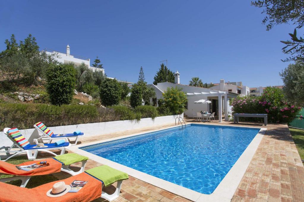 una piscina con 2 tumbonas y una casa en Villa Emilio Pequena by Villa Plus, en Albufeira