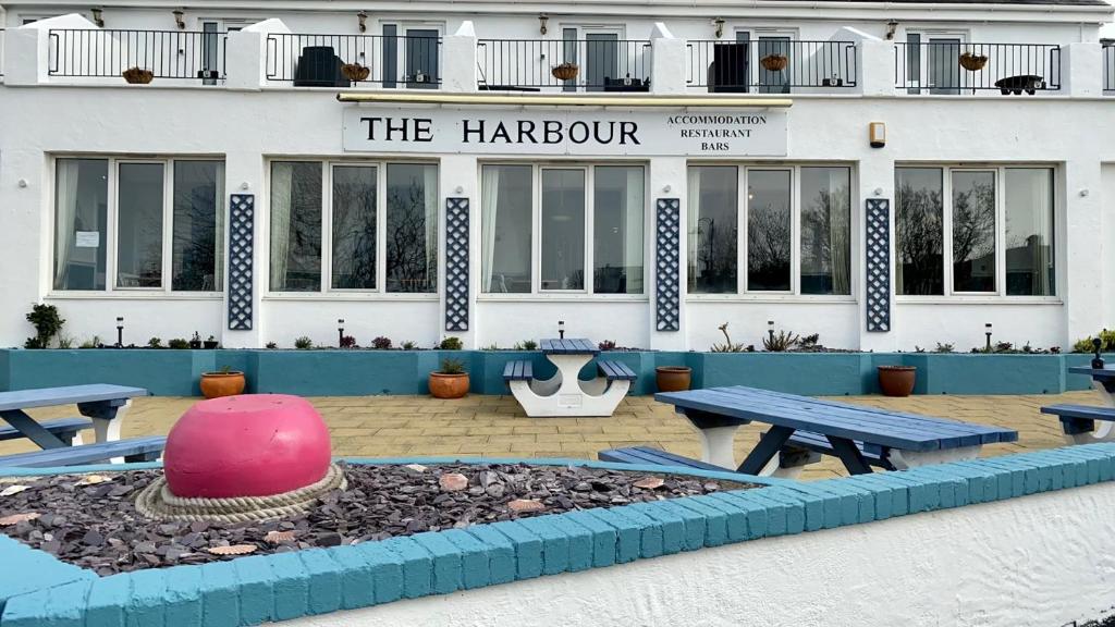 a hotel with tables and benches in front of a building at The Harbour Bar & Bistro in Cemaes Bay