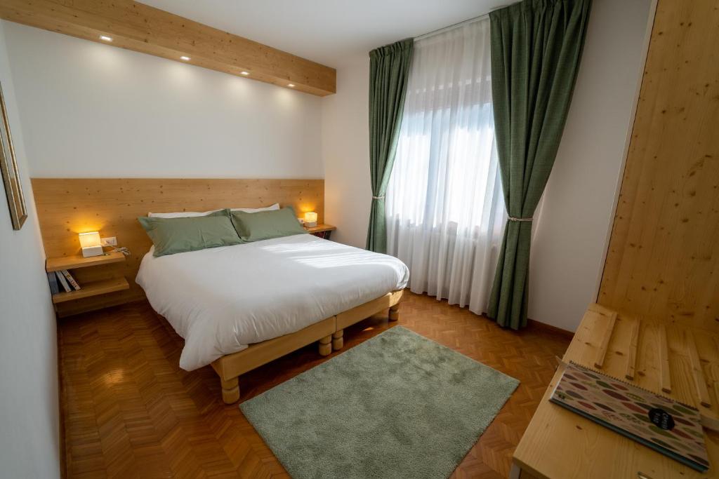 um quarto com uma grande cama branca e uma janela em B&B I FAGGI em Lavarone