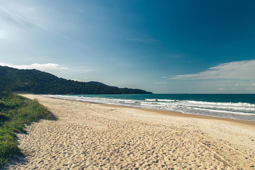 una playa de arena con el océano en el fondo en AP Mar Azul Praia Grande Gov Celso Ramos, en Governador Celso Ramos