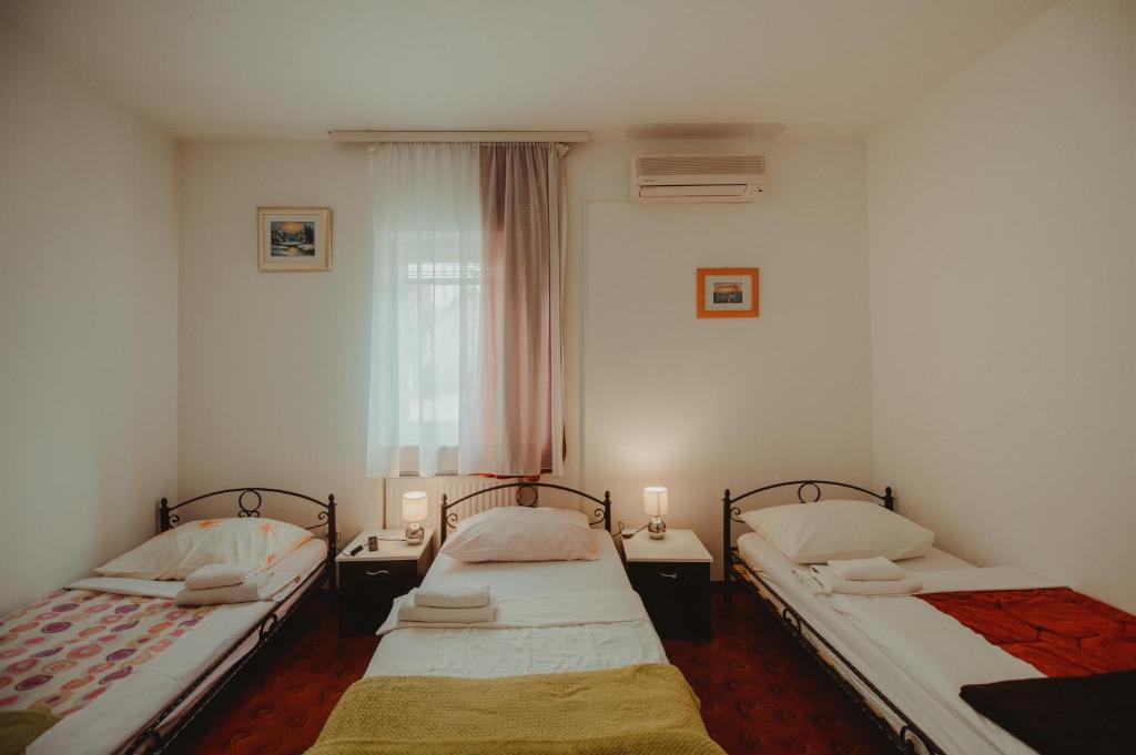 two beds in a small room with two lamps at B&B Laguna in Đakovo