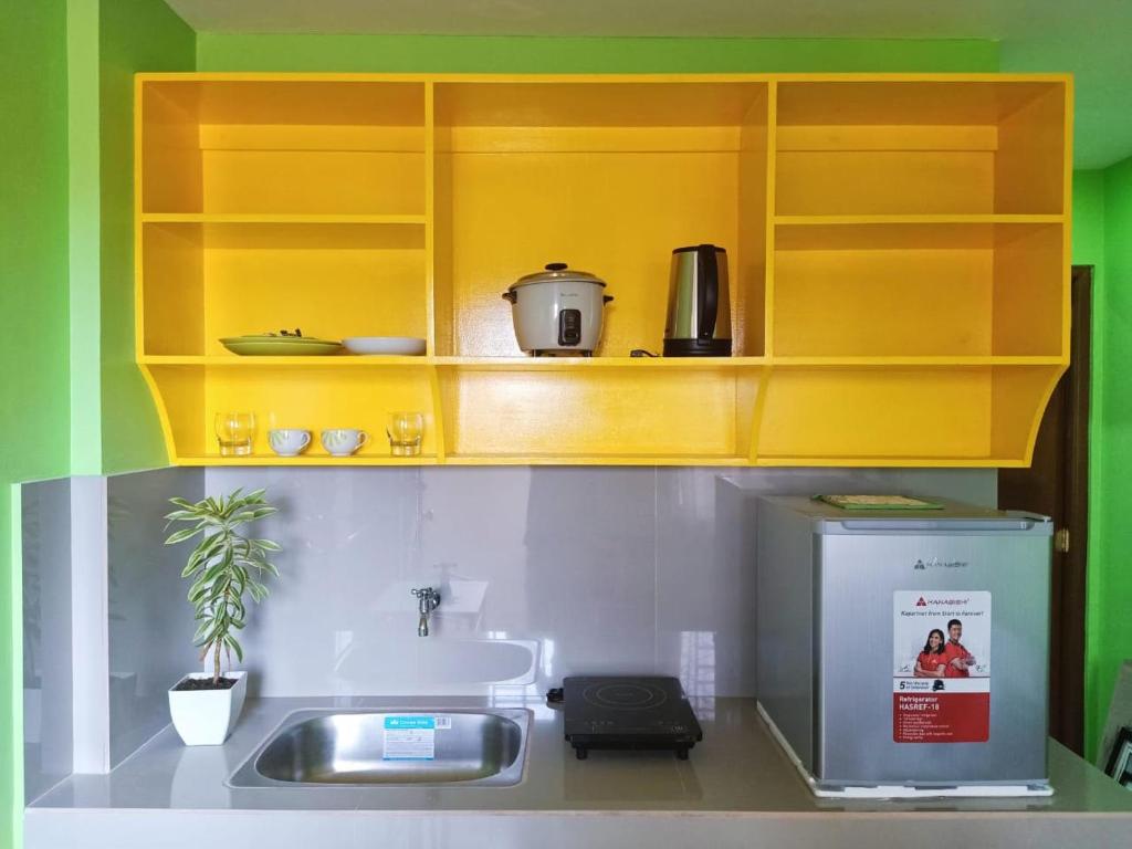 uma cozinha com armários amarelos e um lavatório em Blue Nest Apartment em Manila
