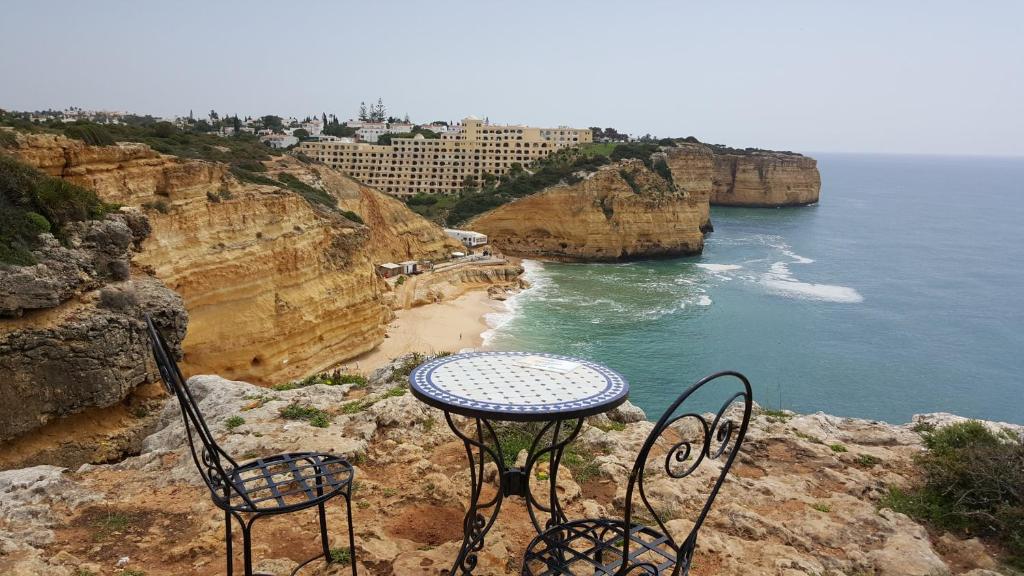 una mesa y sillas sentadas en un acantilado con vistas al océano en Apartamento Limões, en Carvoeiro