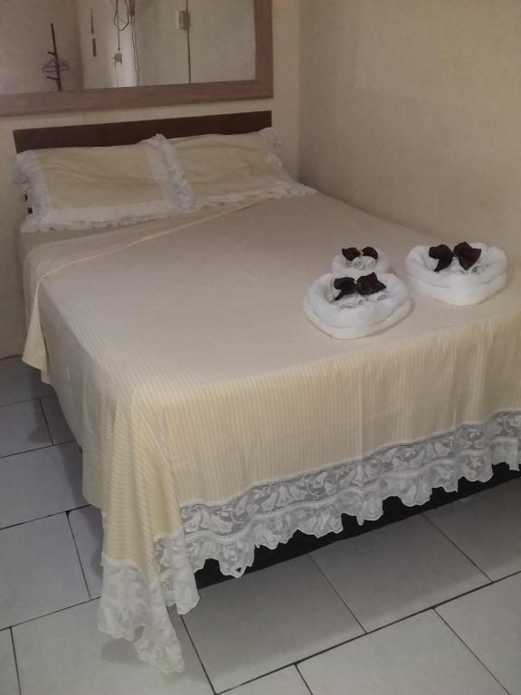 2 camas con toallas y sombreros encima en Pousada do Alex en Campos dos Goytacazes