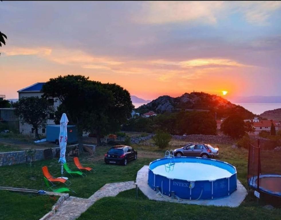 a pool in a yard with a sunset in the background at Apartments Nagj in Sveti Juraj