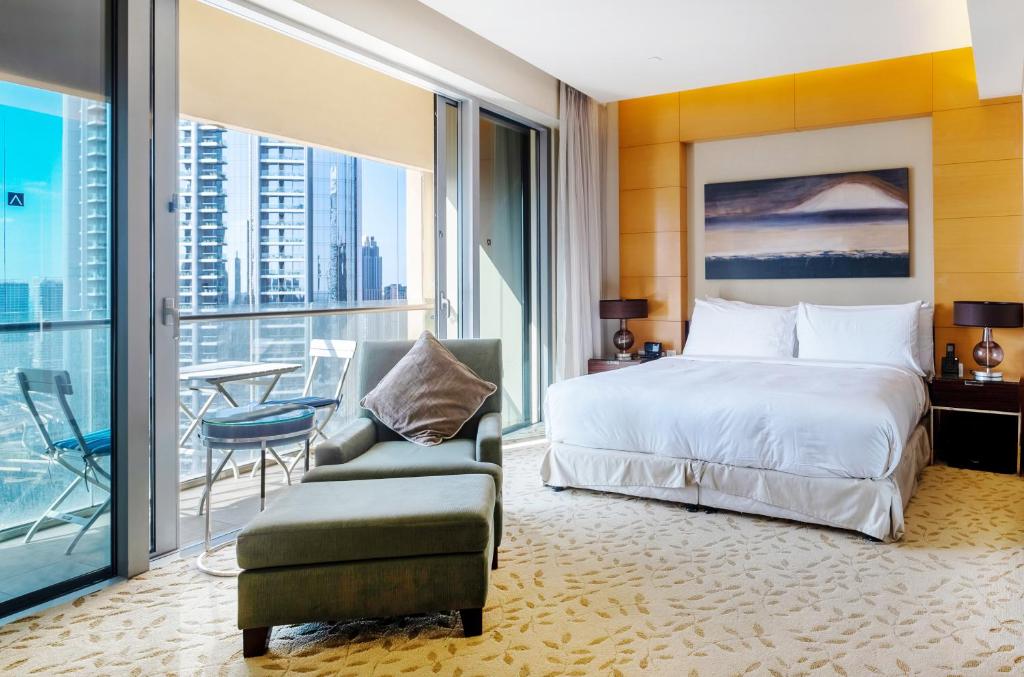 a bedroom with a bed and a chair and a window at Luxury residence at Dubai Mall in Dubai
