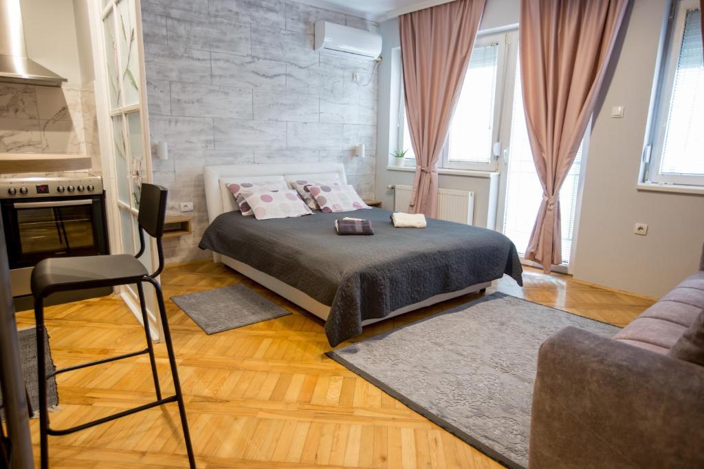 een slaapkamer met een bed en een stoel erin bij Apartment Studio Milena in Subotica