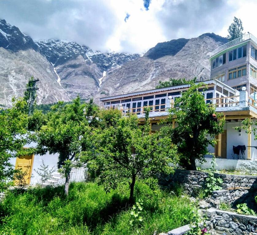 a building with trees in front of a mountain at Tourist Cottage Hunza in Hunza