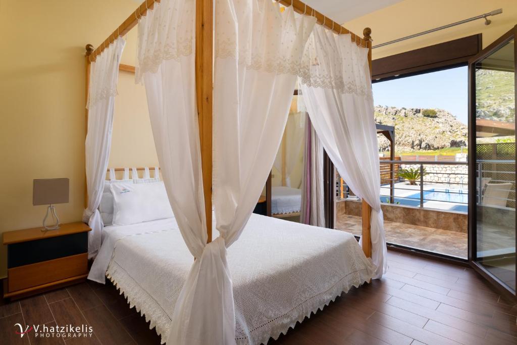 sypialnia z łóżkiem z baldachimem i balkonem w obiekcie Costa Costa Villa - Luxury villa w Kolymbii