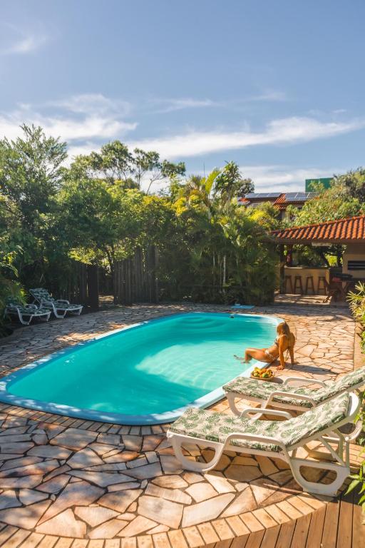 a dog sitting next to a swimming pool at Hospedaria Nativa in Praia do Rosa