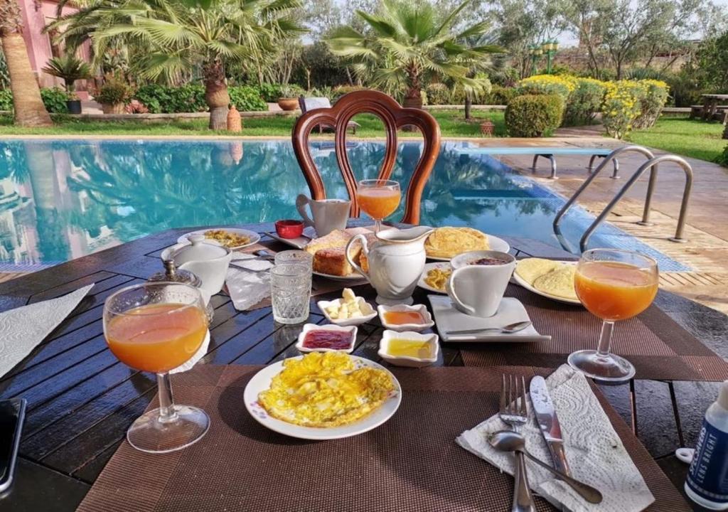 - une table avec petit-déjeuner et boissons à côté de la piscine dans l'établissement Equi Palace & SPA Near Aeroport, à Berrechid