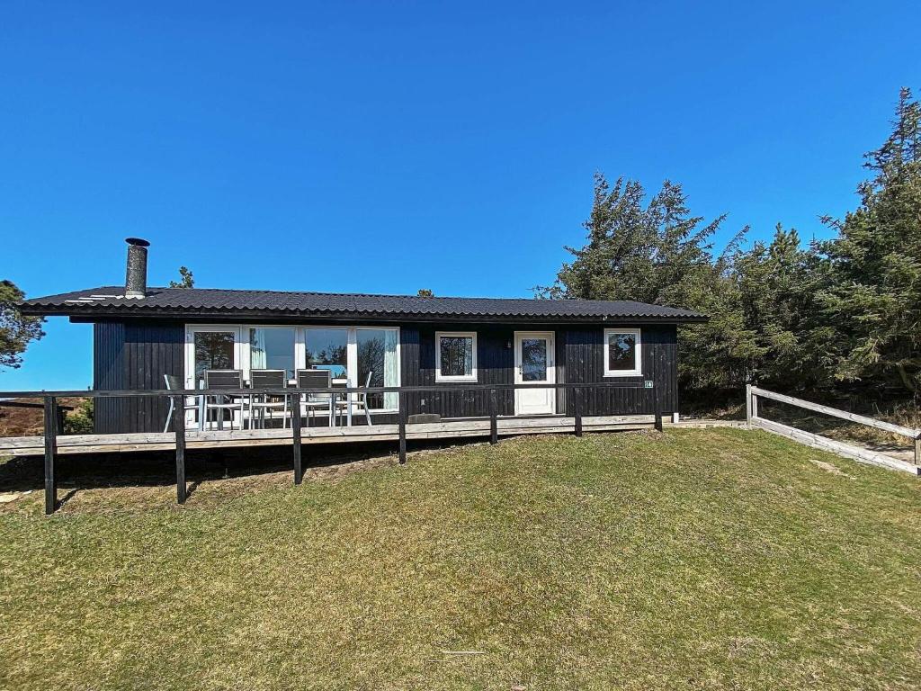 ein schwarzes Haus mit einer Veranda und einem Zaun in der Unterkunft 6 person holiday home in Oksb l in Oksbøl