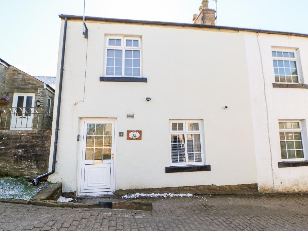 a white house with a white door and windows at Kings Cottage in Alston