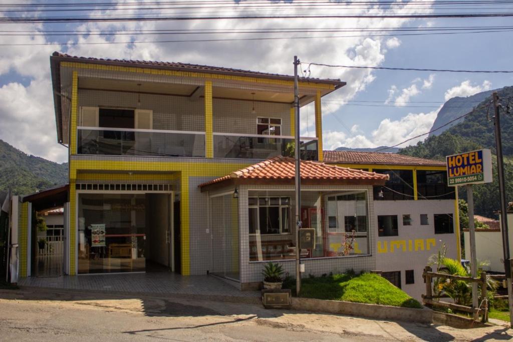 a yellow and white building with mountains in the background at Pousada Hotel Lumiar in Lumiar
