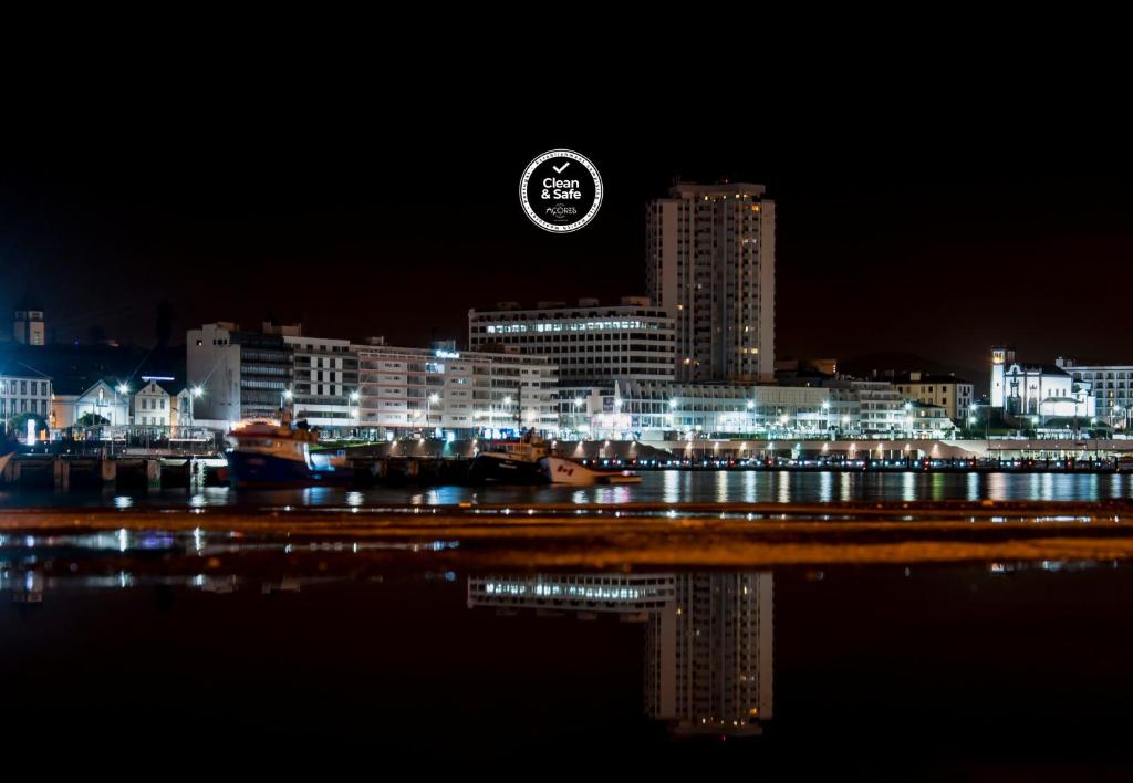 a view of a city at night with a clock at Marina Tower Center in Ponta Delgada