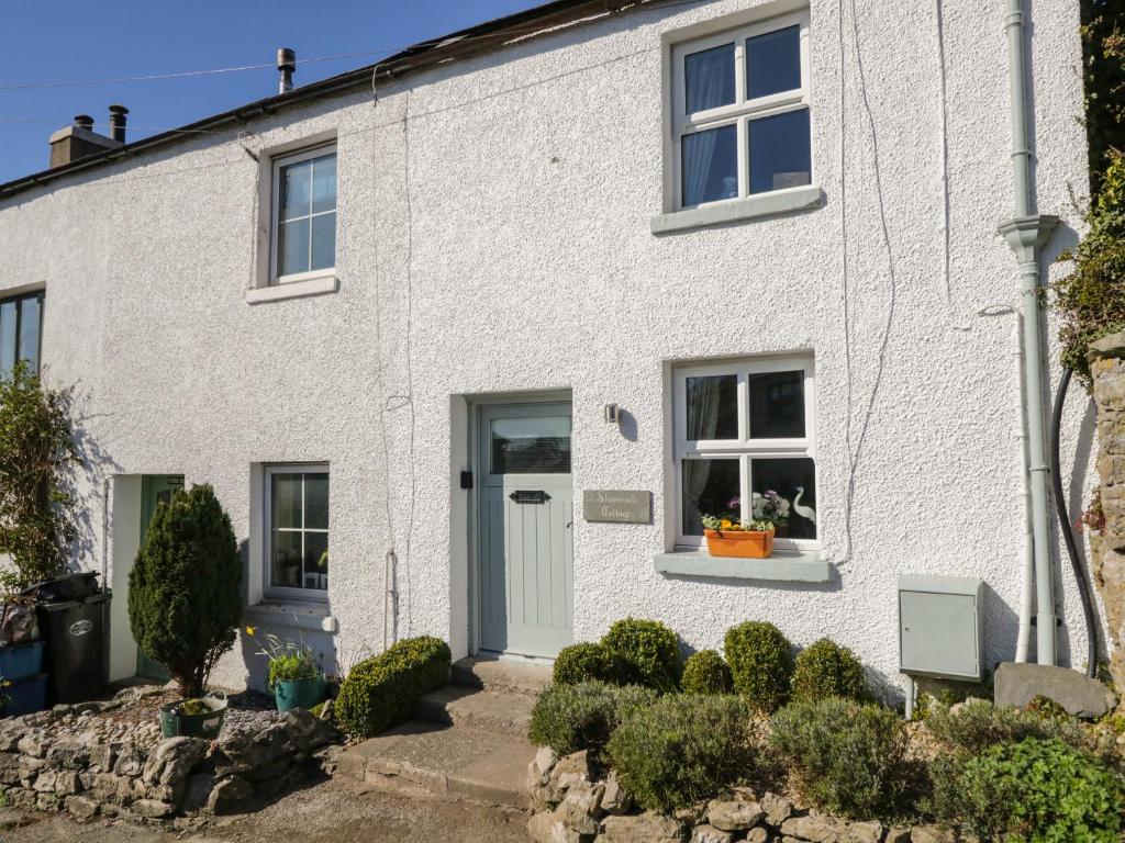 una casa de ladrillo blanco con puerta azul en Shamrock Cottage en Grange Over Sands