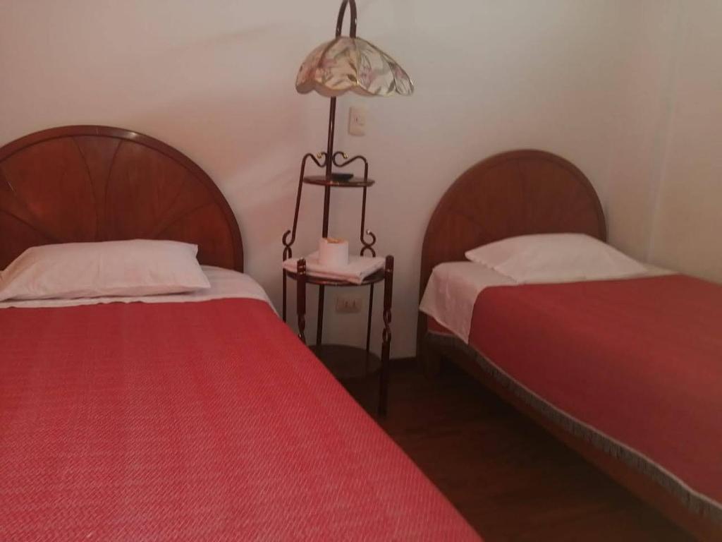 une chambre avec deux lits et une lampe sur une table dans l'établissement Hostal Espinoza II, à Arequipa