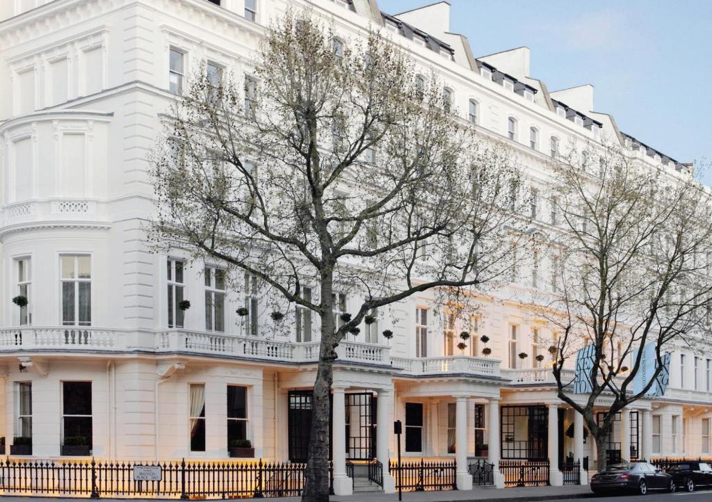 un edificio bianco con un albero di fronte di The Kensington Hotel a Londra