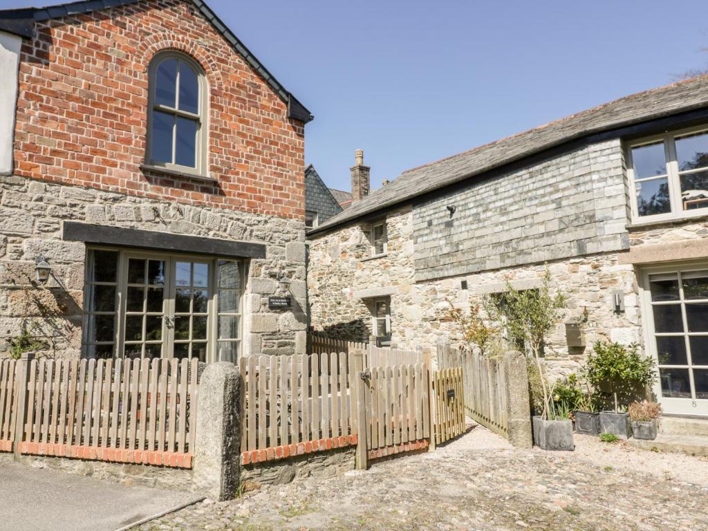 an old stone house with a wooden fence at The Old Smithy in Saint Columb Major