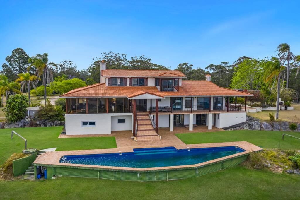 a large house with a swimming pool in front of it at Casa Del Rio - LJHooker Yamba in Ashby