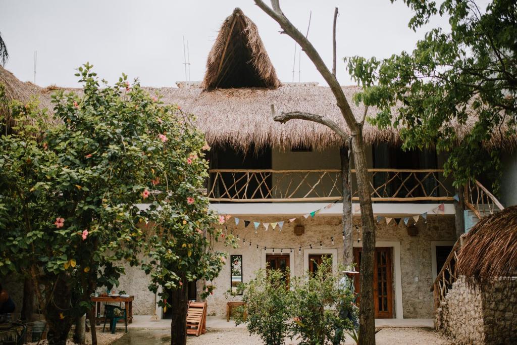 a building with a thatched roof with trees in front of it at Xiknal Cozumel in Cozumel