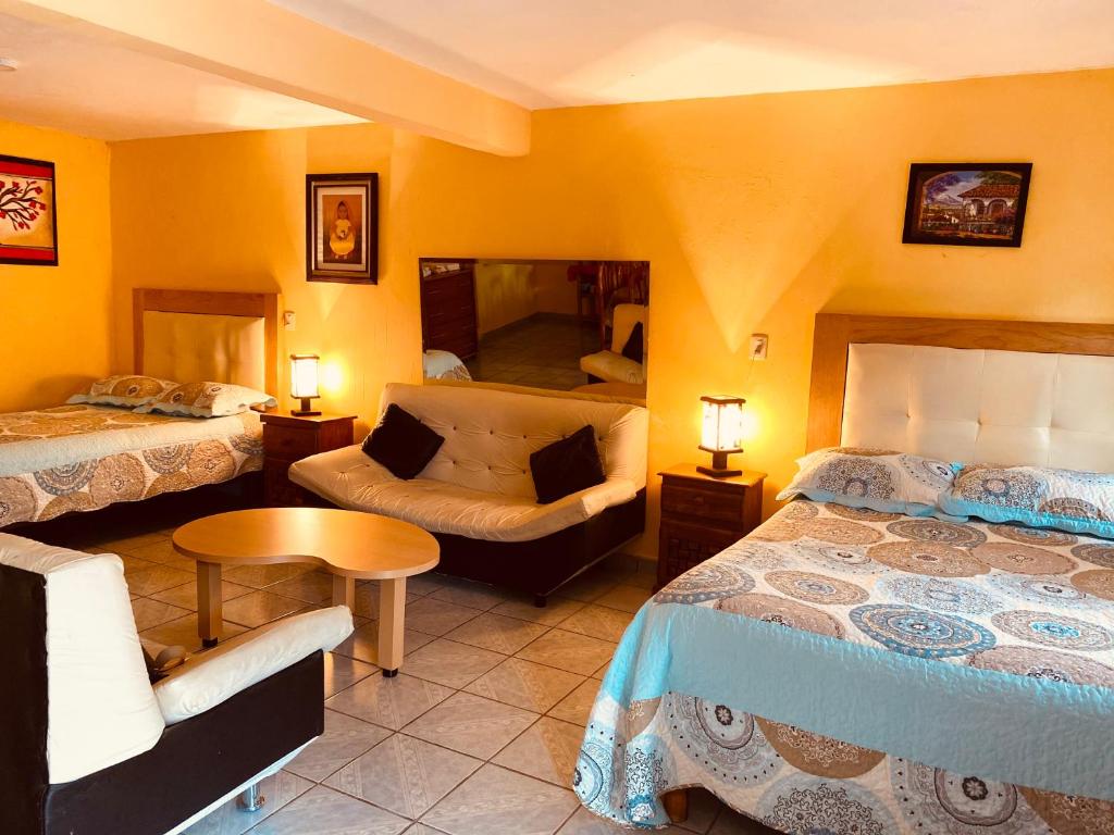 a hotel room with two beds and a couch at El paraíso de Zacatlán DEPARTAMENTO con JARDÍN, 11 pax in Zacatlán