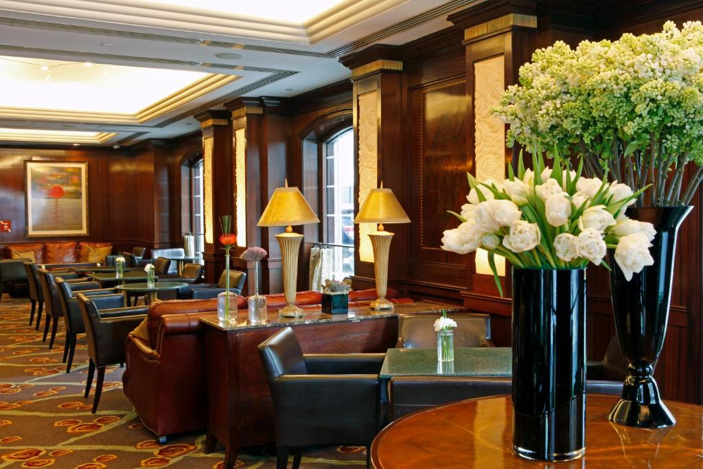 a lobby with tables and chairs and a vase of flowers at Warwick New York in New York