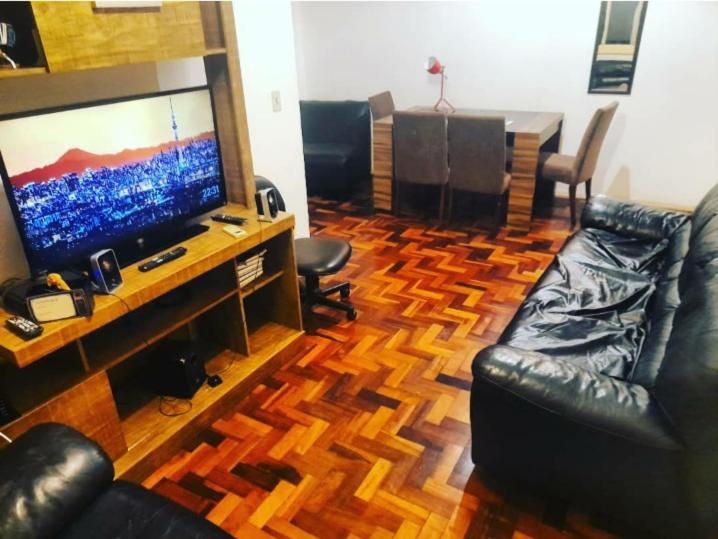 uma sala de estar com uma televisão de ecrã plano e mobiliário em couro em Apartamento Jardim Botânico 3 quartos 3 vagas para carro em Porto Alegre