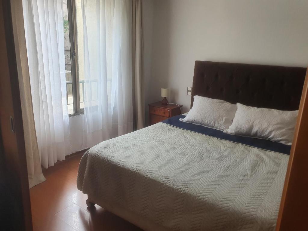 1 dormitorio con cama y ventana en Barrio Lastarria, Departamento 2 ambientes, en Santiago