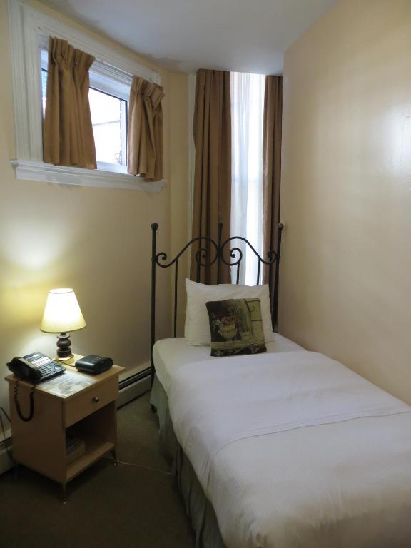 a bedroom with two beds and a lamp and a window at Victoria's Mansion Guest House in Toronto
