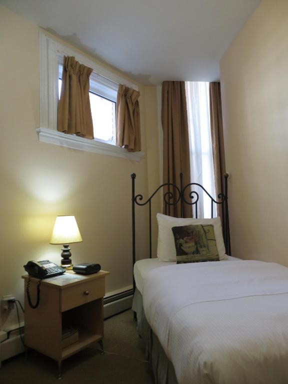 a bedroom with a bed and a lamp and a window at Victoria's Mansion Guest House in Toronto