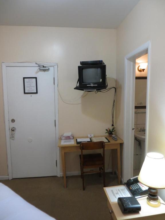 a room with a desk and a tv on the wall at Victoria's Mansion Guest House in Toronto
