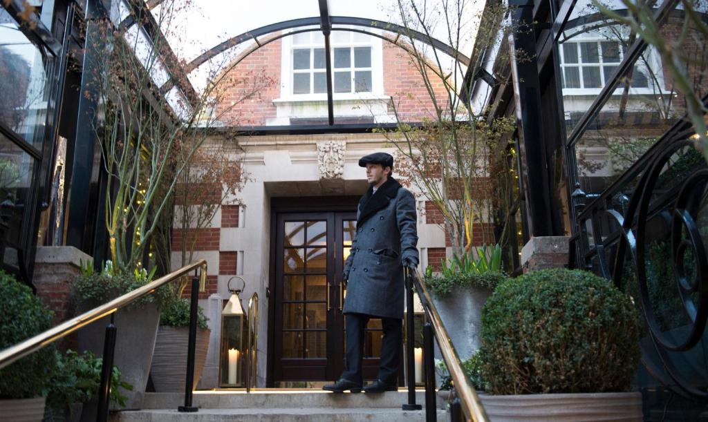 a man in a suit and tie standing in front of a building at The Bloomsbury Hotel in London