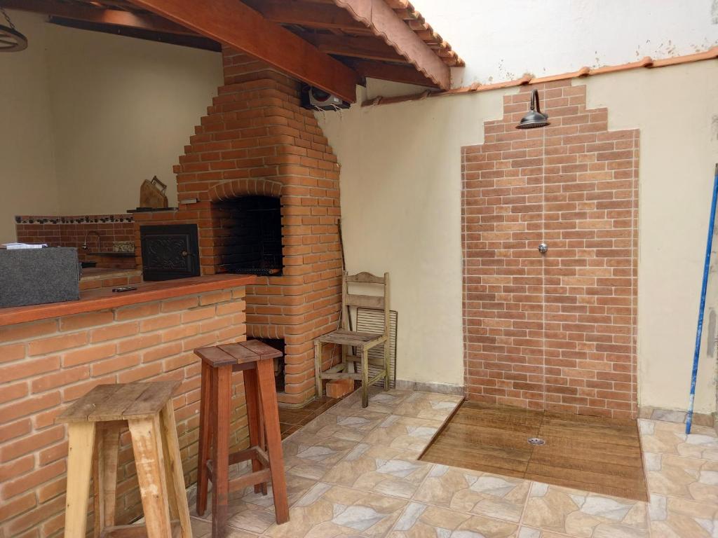 uma lareira de tijolos com dois bancos num quarto em Casa Azul no Centro Ilha Comprida em Ilha Comprida
