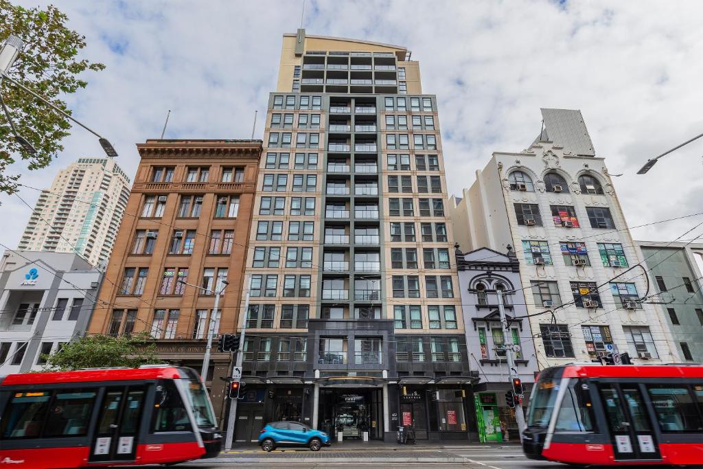 eine Stadt mit zwei Bussen vor hohen Gebäuden in der Unterkunft Mantra Sydney Central in Sydney