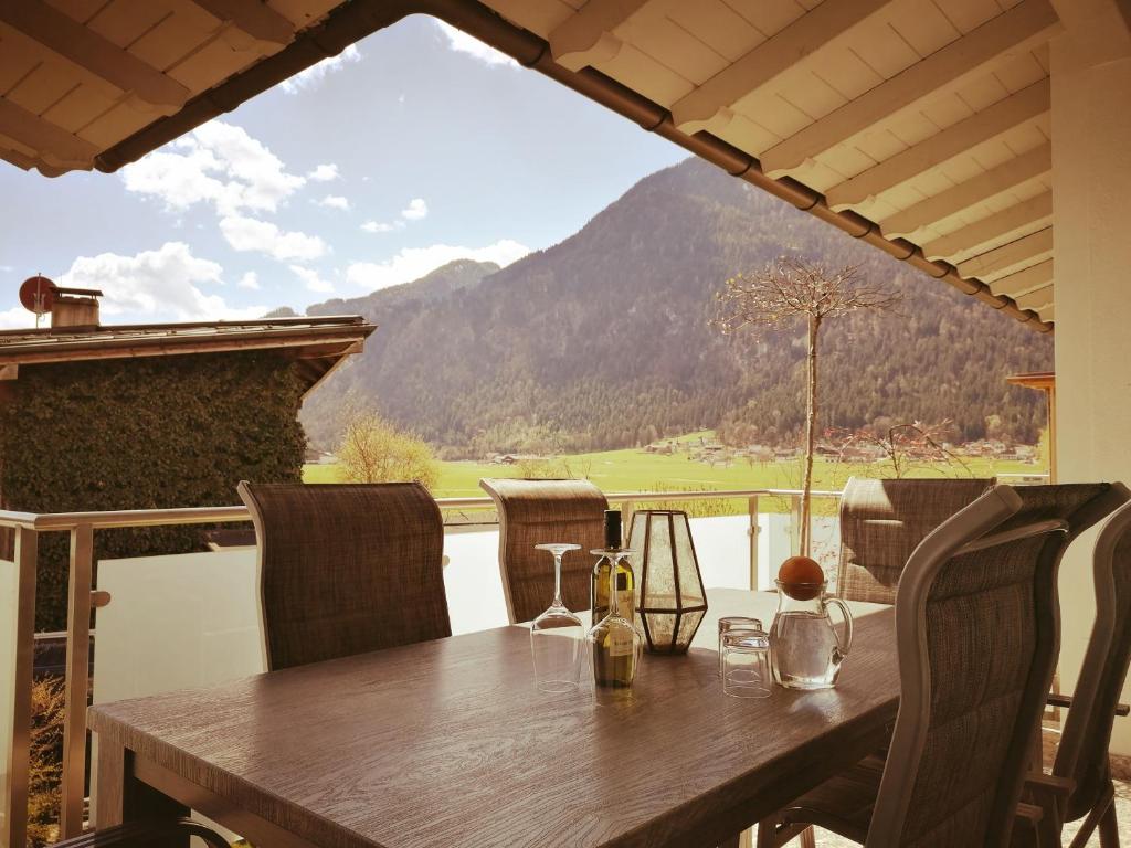 una mesa de madera con sillas y vistas a la montaña en Ferienwohnungen Strass im Zillertal, en Strass im Zillertal
