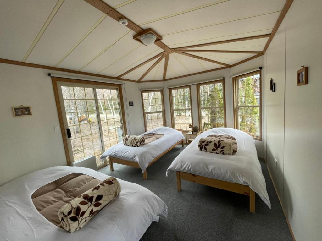 two beds in a room with windows at Hakuba Canadian Lodge in Hakuba
