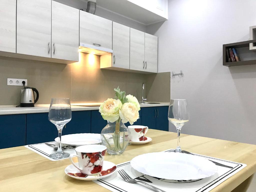 a kitchen with a table with plates and wine glasses at Новые апартаменты в ЖК БАРСКИЙ in Yakushintsy