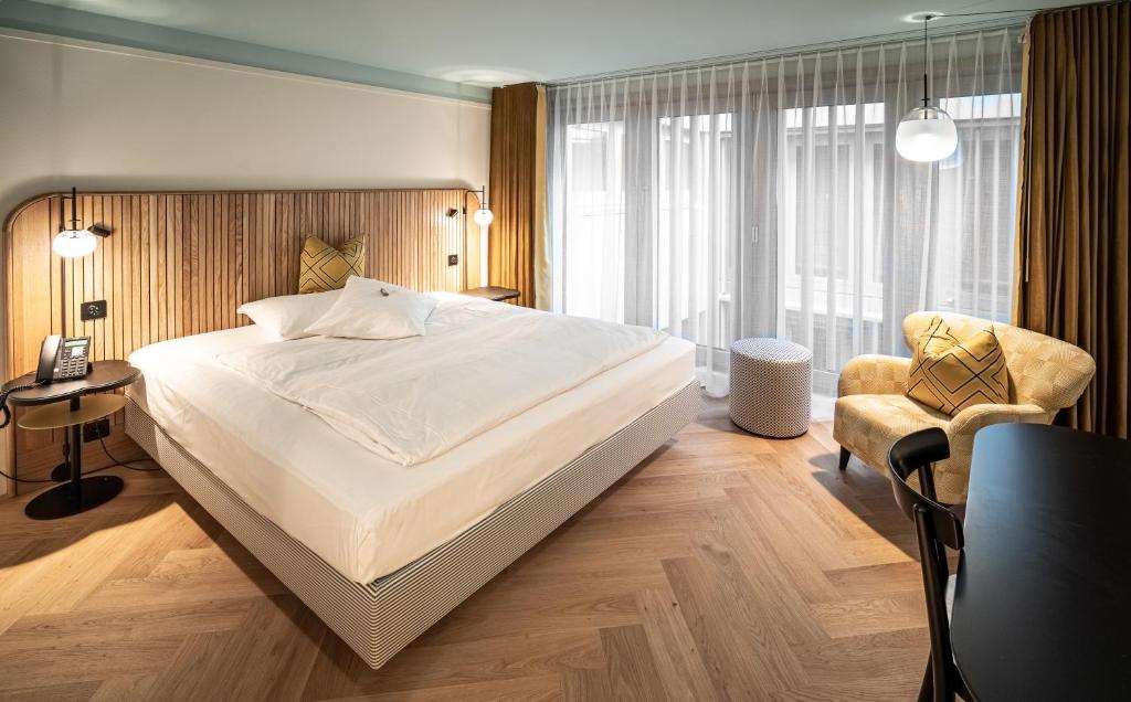 Best Western Plus Hotel Bern في برن: غرفة نوم بسرير كبير وكرسي